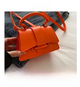 Gros plan d'un mini sac à main en cuir orange vif posé sur une veste en jean bleue