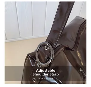 Detail of dark brown glossy tote bag with adjustable shoulder strap and metal buckle