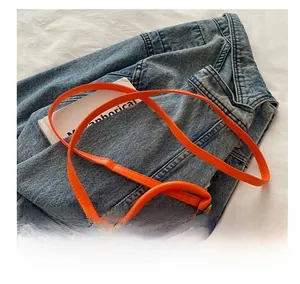 Détail d'un mini sac à main en cuir orange vif avec poignée ronde et bandoulière réglable