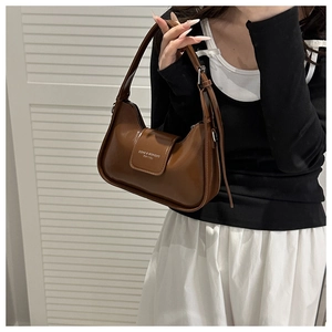 Elegante bolso baguette de cuero marrón brillante mostrado por una modelo con estilo