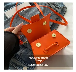 Vue détaillée du sac bandoulière orange montrant les fermoirs magnétiques et l'intérieur