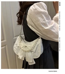 Close-up of white lace shoulder bag featuring a large satin bow and elegant pearl handle
