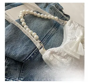Detailed close-up of metal rings connecting the bow handbag with pearl bead strap