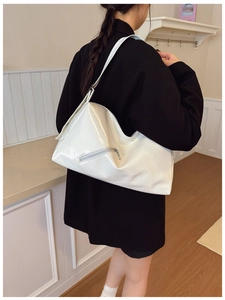 Close-up of a white glossy leather hobo tote bag with silver zipper and metallic buckles