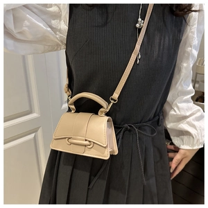 Mini sac beige avec boucles dorées porté sur une robe rayée, vue détaillée du sac