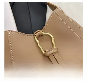 Détail d'un fermoir anneau ondulé doré sur un sac à bandoulière en cuir marron vintage