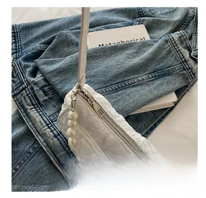 Detailed macro view of white pleated handbag with elegant pearl strap and metal zipper