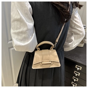 Gros plan du mini sac à bandoulière beige avec boucle ronde sur un modèle