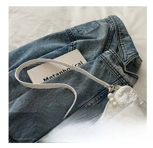 Detail of white quilted bag featuring a large bow and elegant pearl bead handle