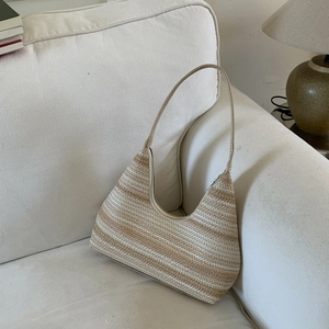 Bohemian striped straw hobo shoulder bag with moon shape on a minimalist sofa