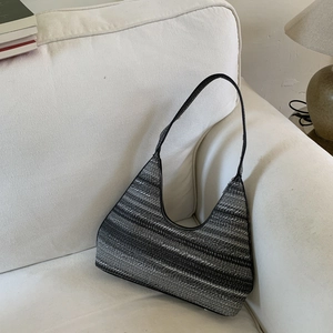 Detailed view of woven striped shoulder bag with a high-end texture on a minimalist sofa