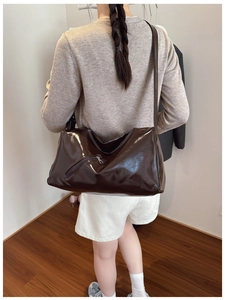 Detail of vintage brown patent leather tote bag with glossy finish and front zipper pocket