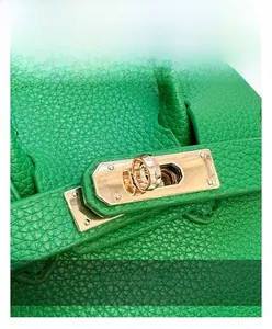 Detail view of gold-tone metal twist lock on green lychee pattern leather handbag