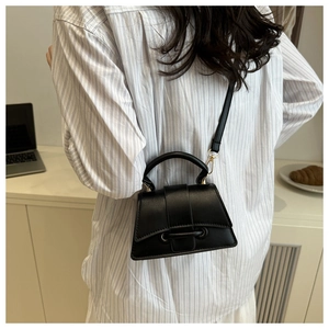 Sac à main chic en cuir noir porté par un mannequin dans un cadre urbain décontracté
