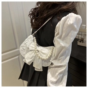 Detail of white jacquard half-moon bag with large satin bow and pearl shoulder strap
