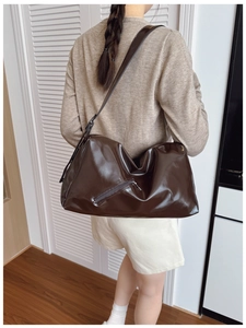 Close-up of deep chocolate brown patent leather tote bag with functional side zipper
