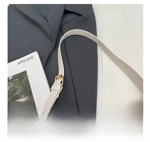 Detail view of adjustable white leather shoulder strap with gold buckle and stitching