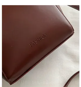Détail du sac seau en cuir marron foncé avec logo FASHION embossé et coutures