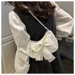 Detail of white lace crescent bag with large chiffon bow and decorative pearl chain