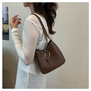 Détails d'un sac seau marron rétro avec surpiqûres blanches et boucle en métal doré