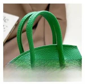 Detailed macro view of the bright green lychee grain leather handbag and top handles