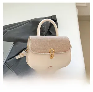 Detail of crossbody bag featuring gold horseshoe buckle and textured fabric flap