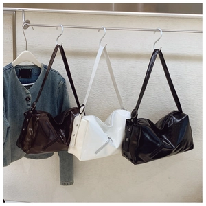 Detail view of glossy leather shoulder bags in black, white and brown with metal hardware