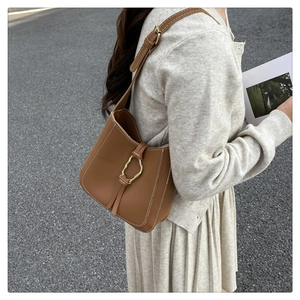 Détail d'un sac seau en cuir marron avec surpiqûres blanches et boucle dorée élégante