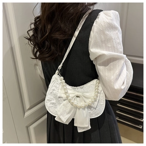 Close-up of white lace shoulder bag with silk bow and elegant pearl handle strap