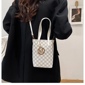 Detail of white crossbody bag with grey M monogram print and metal letter pendant