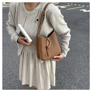 Détail du sac seau en cuir marron avec anneau doré et surpiqûres blanches contrastées