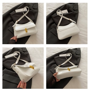 Detail of white patent leather baguette bag with gold pill-shaped clasp and mirror finish