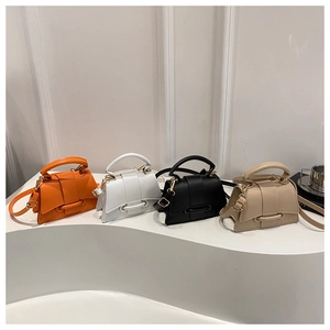 Série de mini sacs trapèze en orange, blanc, noir et beige sur un support d'exposition blanc