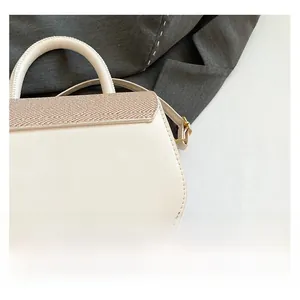 Detail of cream crossbody bag featuring woven texture flap and metallic hardware