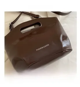 Detail of dark brown patent leather tote with cutout handle and FASHION & BAGS logo