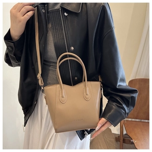 Détail d'un sac seau beige chic avec bandoulière réglable et logo fashion embossé