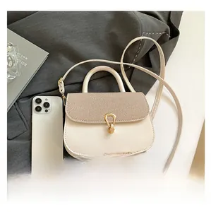 Detail of mini saddle bag with contrast woven texture and gold clasp next to a smartphone