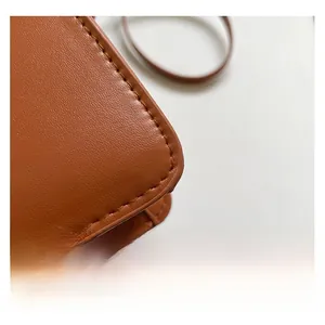 Vue macro de la texture du sac en cuir marron avec coutures soignées et finition de qualité