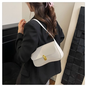 Detail view of a white minimalist underarm bag with a gold cylindrical rotating lock buckle