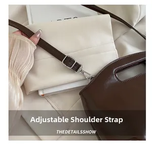 Detail view of adjustable leather shoulder strap and silver hardware on a dark brown bag