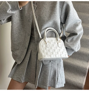 Close-up of white embossed shell handbag with a textured checkerboard pattern and gold hardware