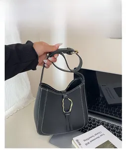 Détail du sac bandoulière en similicuir noir avec surpiqûres blanches et boucle dorée