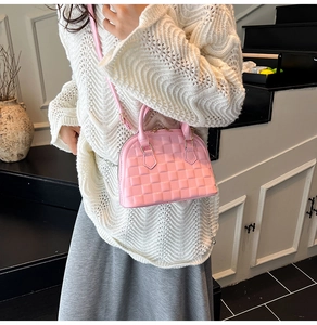 Pink jelly shell bag with embossed square patterns worn by model in minimalist setting
