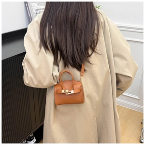 Detail shot of a mini caramel trapezoid bag with lychee texture and gold buckle