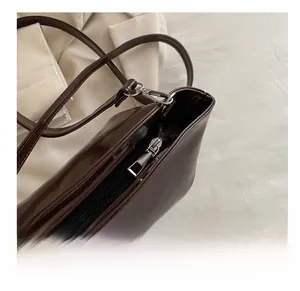 Detailed macro view of the smooth silver zipper and dark brown leather texture of the bag
