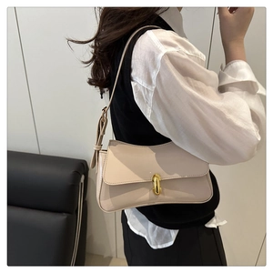 Close-up of off-white leather underarm bag with elegant gold lock and adjustable strap
