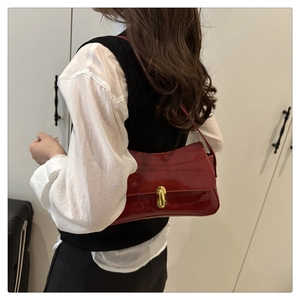 Detail of red patent leather shoulder bag with gold metal twist lock on model