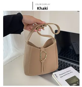 Détail du sac à bandoulière kaki avec surpiqûres blanches et boucle en métal doré