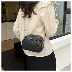 Close-up of black quilted PU leather crossbody bag with dual zippers and chain strap