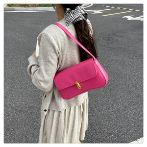 Detail of magenta square underarm bag with gold oval twist lock shown on model shoulder